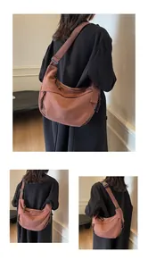 Détail du sac bandoulière demi-lune rouille avec large sangle et tirette de zip tissée à la main