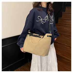 Detailed view of khaki canvas tote bag featuring black leather handles on wooden stairs