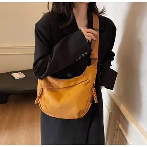 Détail du sac bandoulière jaune moutarde en suède avec bandoulière sur modèle