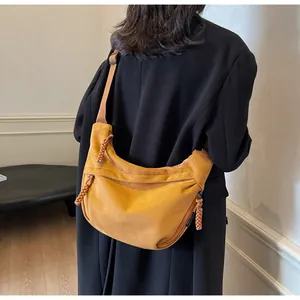Détail du sac bandoulière jaune moutarde avec fermeture éclair tressée et daim doux