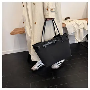 Close-up of black canvas tote bag with adjustable leather straps and silver metal buckles
