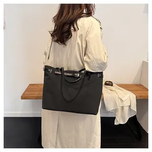 Detail view of a large black canvas tote bag showing the leather drawstring and handle texture