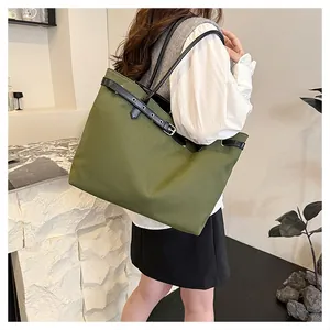 Detail view of large olive green canvas tote bag with black leather buckle strap detail