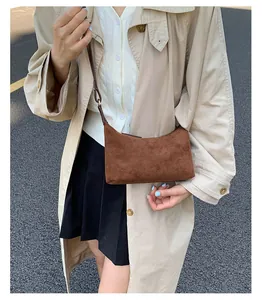 Brown suede crossbody bag shown on a model wearing a beige trench coat for a street style look