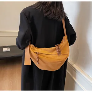 Detail of ginger yellow crossbody dumpling bag with woven zipper and wide strap on model