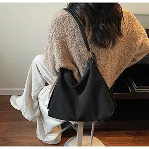 Détail du sac hobo noir minimaliste montrant la texture mate et la bandoulière en cuir