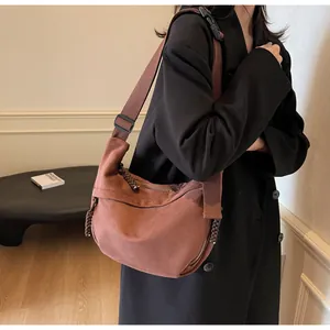 Détail du sac demi-lune en toile marron foncé avec fermeture éclair et bandoulière large