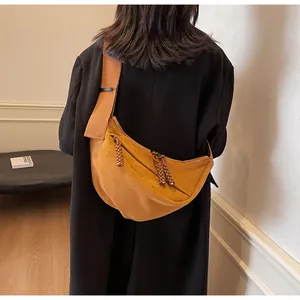 Detail of the caramel suede crescent bag showing the wide strap and braided zipper pull