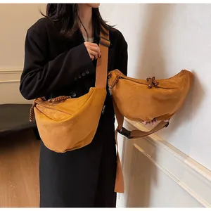 Detail of suede crescent bag showing woven zipper pulls and adjustable woven strap