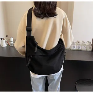 Détail de la bandoulière large réglable sur un sac besace en toile noire demi-lune