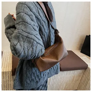 Detailed view of brown pleated crescent shoulder bag with metallic zipper and fine texture