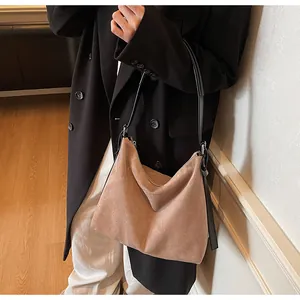 Gros plan d'un cabas en daim marron avec bandoulière en cuir noir sur un mannequin