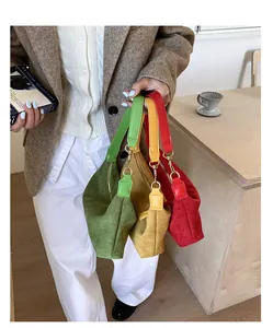 Three suede handbags in green, yellow, and red with elegant gold zippers and curved design