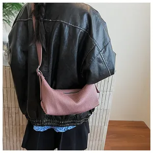 Detail of pink pleated crescent bag showing unique texture and adjustable strap on model