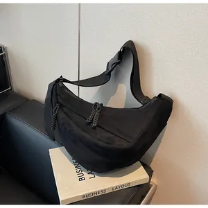Detail view of black crescent crossbody bag with braided zipper pull and adjustable strap