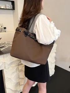 Large dark brown canvas tote bag with black leather straps shown from a side view