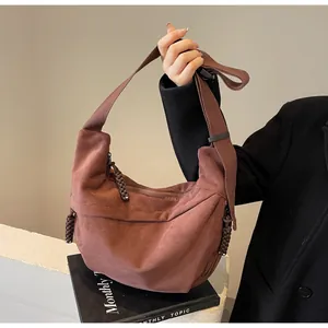 Détail d'un sac bandoulière demi-lune marron avec tirette tressée et bandoulière large