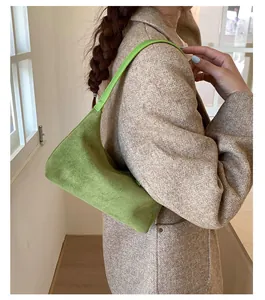 Detail of green suede underarm bag showing textured finish and minimalist shoulder strap