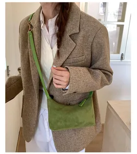 Close-up of a green suede hobo bag styled with a brown blazer in a cozy indoor setting