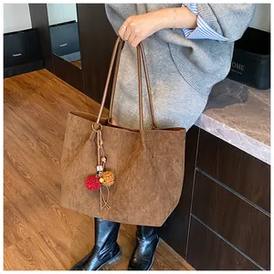 Detail of retro brown suede tote bag with decorative colorful plush pompom tassel
