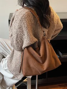 Grand sac cabas hobo marron en faux daim mat, porté à l'épaule par un mannequin chic