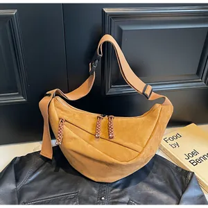 Detail of ginger suede crescent bag with textured shoulder strap and braided zipper pulls