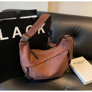 Détail du sac bandoulière marron en forme de croissant sur un canapé en cuir chic