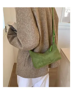 Close-up of grass green suede crescent bag with adjustable strap and metal hardware