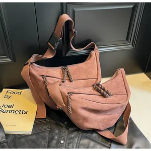 Detail of brown suede crescent bags with wide straps and woven rope zipper pulls