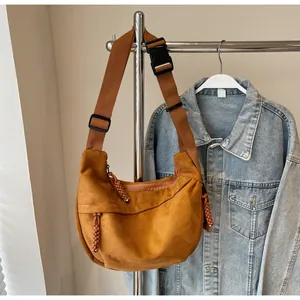Détail du sac demi-lune en daim caramel avec large bandoulière et boucle de fermeture