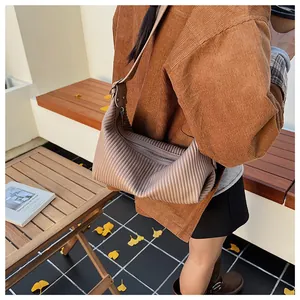 Close-up of brown pleated dumpling bag with top zipper and adjustable shoulder strap