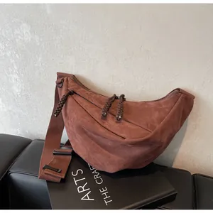 Close-up of caramel suede crescent crossbody bag with woven knot detail and wide strap