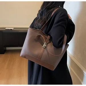 Detailed view of dark brown pebbled leather tote bag featuring a metallic lock buckle