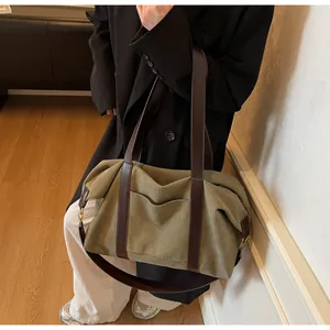 Detail of olive canvas tote bag featuring brown leather straps and front pocket design