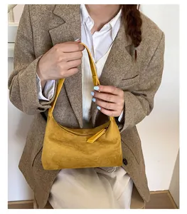 Detail of ginger yellow suede handbag featuring smooth zipper and premium texture