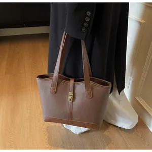Detail of a brown lychee grain leather tote bag with gold metal lock and dual handles