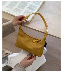 Macro detail of yellow suede dumpling bag with leather strap and golden hardware