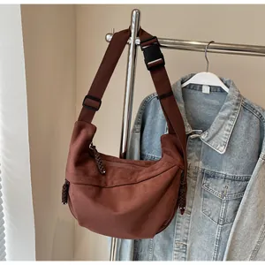 Gros plan d'un sac demi-lune en toile marron foncé avec sangle en nylon et tirette cordée