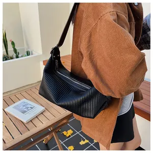 Detail of black pleated faux leather surface and silver zipper on a crescent bag
