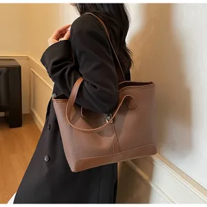 Close-up of textured litchi leather tote bag with vertical strap and metal buckle detail