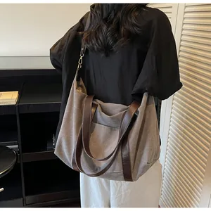Detail of large canvas tote bag showing grey fabric with dark brown leather straps