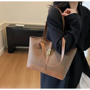 Detailed close-up of brown pebbled leather tote bag with elegant gold twist lock closure
