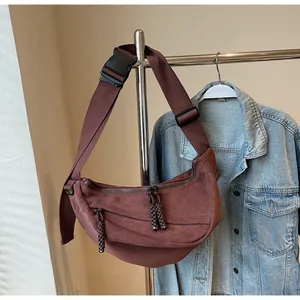 Detail of coffee brown crossbody crescent bag with wide woven strap and zipper cord