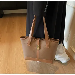Detail of a brown leather tote bag with a golden turn-lock and pebbled texture for work