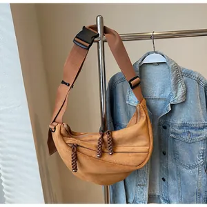 Detailed close-up of brown suede half-moon crossbody bag with adjustable wide strap