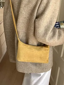 Minimalist ginger yellow matte leather tote bag worn with a grey tweed coat for daily fashion
