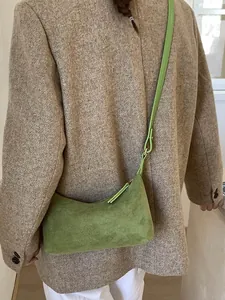 Minimalist green suede half-moon shoulder bag styled with a brown tweed blazer