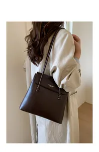 Detail of dark brown lychee leather bucket bag showing gold text and slender strap