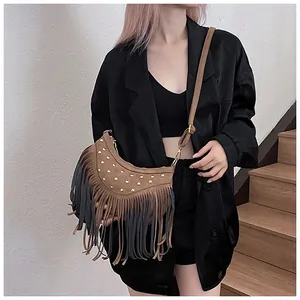 Detail of brown suede crossbody bag with vintage rivets and long fringe tassels