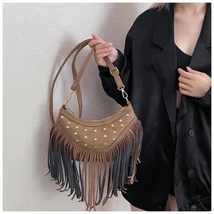 Détail du sac en daim marron avec rivets dorés et longues franges décoratives